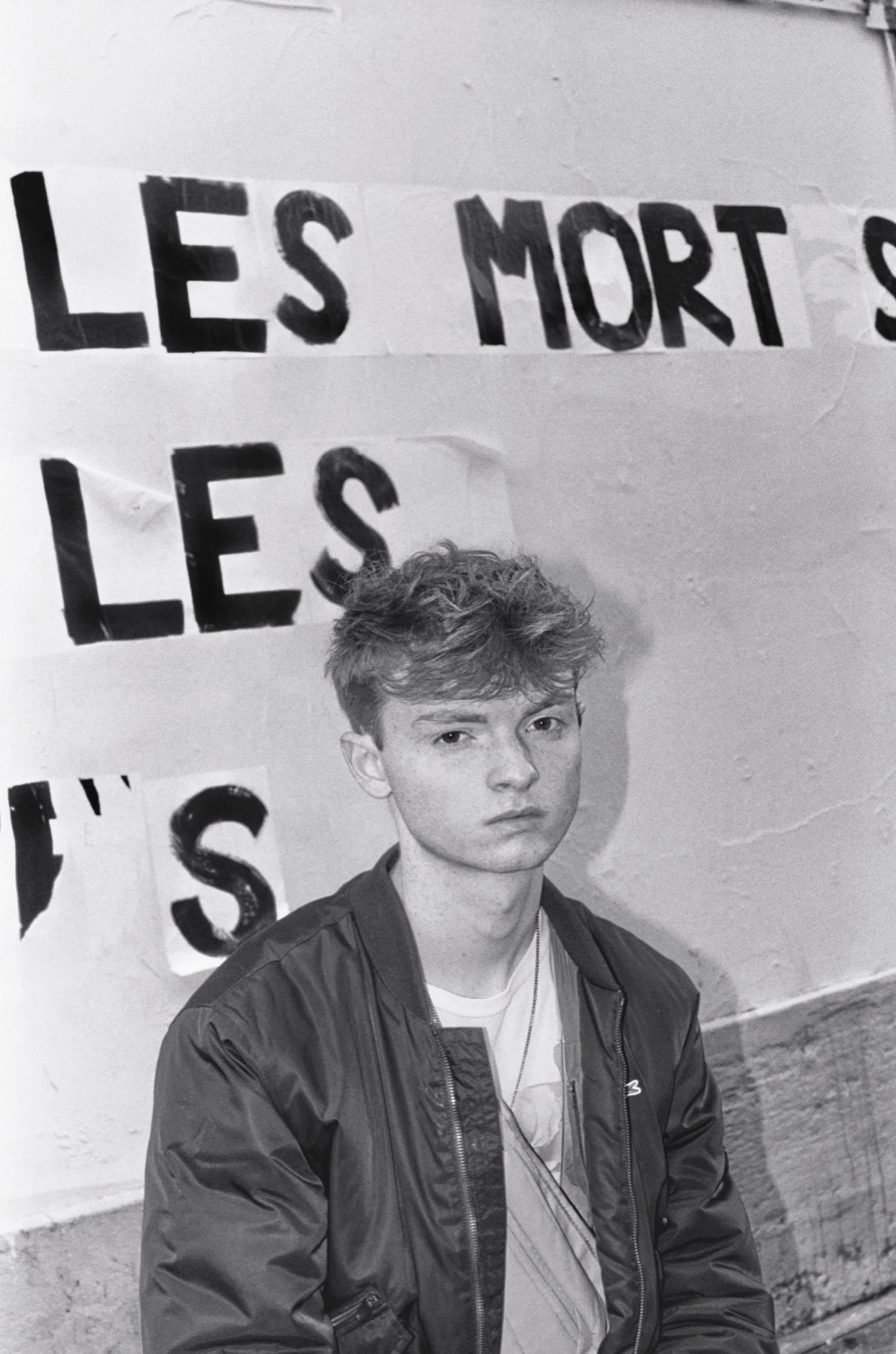 Black-and-white portrait beside Paris street posters