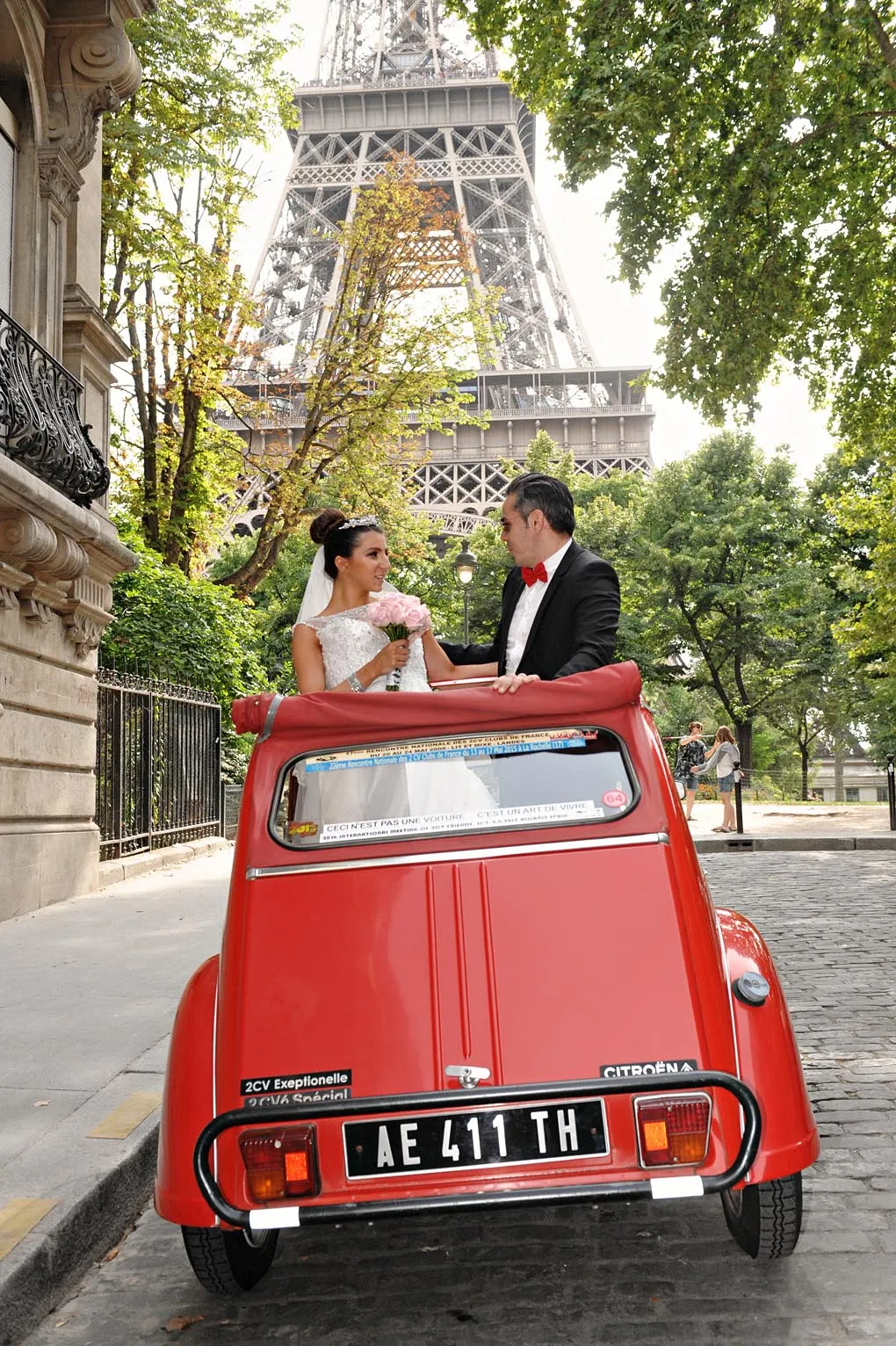Newlyweds in a red vintage car beneath the Eiffel Tower