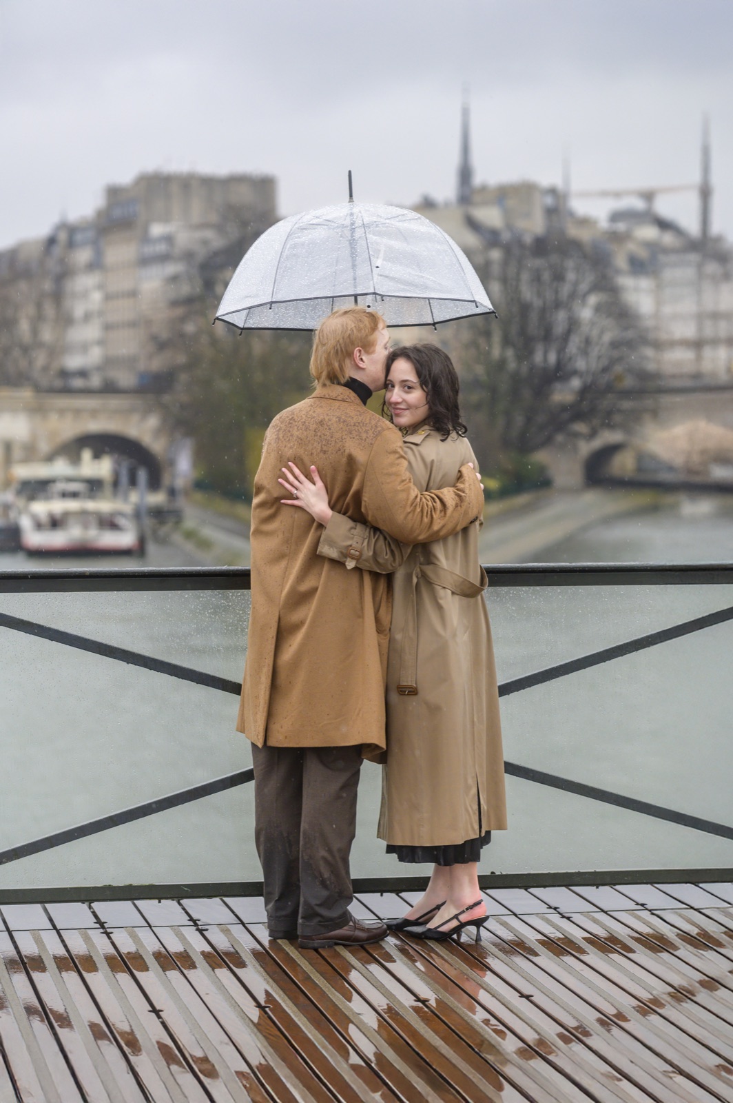 A newly engaged couple embracing in the rain