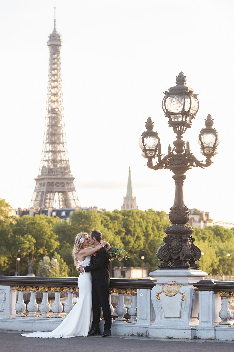 Newlyweds embracing beside the Eiffel Tower in Paris